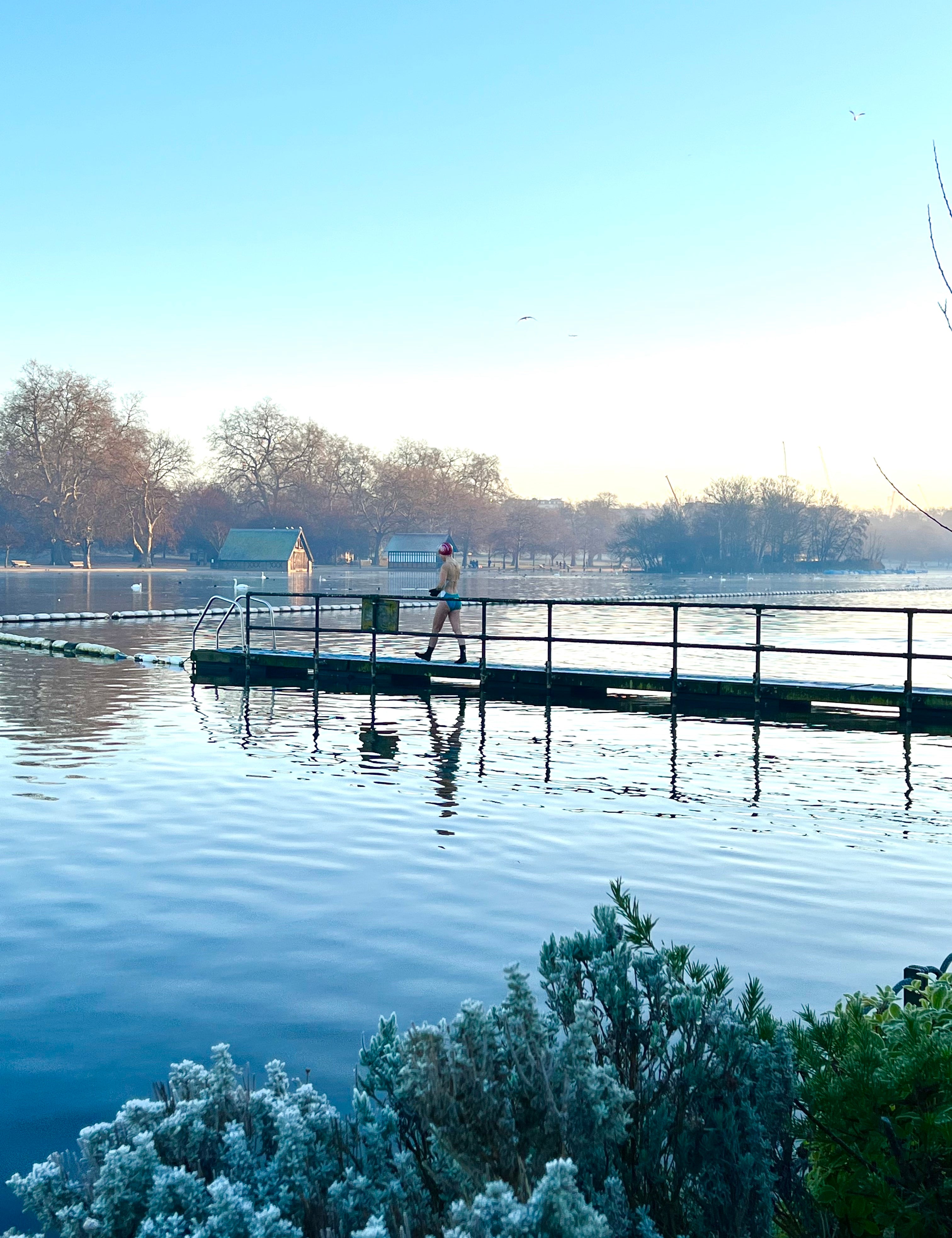 a figure walks on a frozen dock in the Serpentine in Hyde Park before swimming.